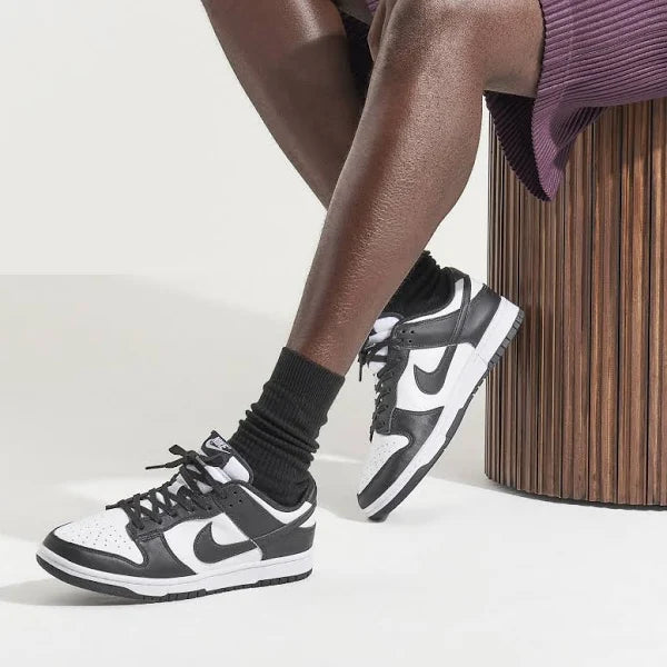 Model wearing Jordan 1 Low 'Panda' sneakers, styled with black socks and a skirt, showcasing the versatile and trendy appeal of the shoe.