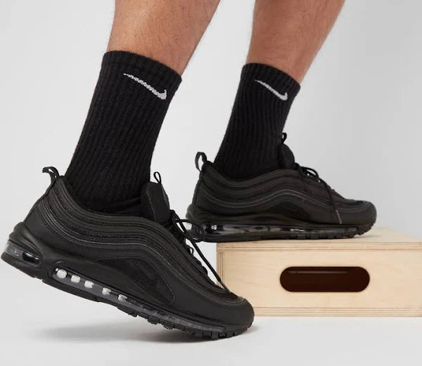 Nike Air Max 97 'White/Black' in black worn with black socks, demonstrating its sleek design and comfortable fit for everyday wear.