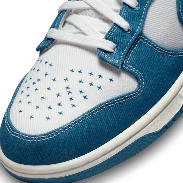 Close-up of Nike Dunk Low ‘Industrial Blue’ toe box, featuring embroidered star details, white leather base, and blue denim overlays for a unique touch.